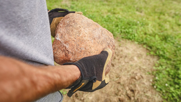 A hunter holding a Redmond Trophy Rock prepares to set up a deer mineral site.